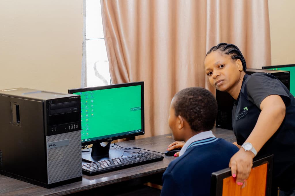 An Izma team member helping a student at a computer