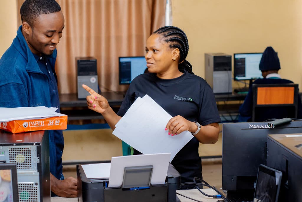 Izma team members talking while holding printed papers